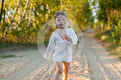 A little girl in a white traditional Ñhemise running in a scenic early autumn landscape Stock Photo