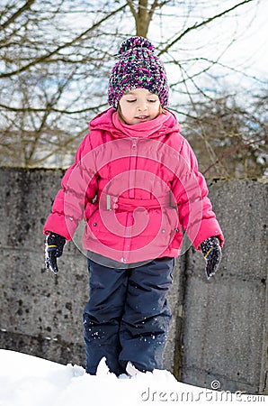 Little girl in winter clothes is playing in snow with snow on he Stock Photo