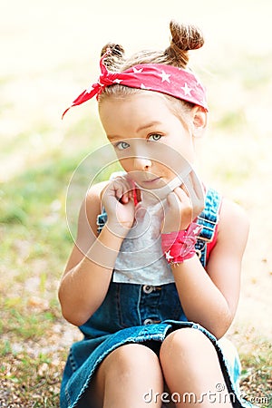 Little girl wipes her mouth with a napkin. A child with a hair tail and a red bandana Stock Photo