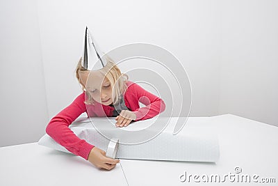 Little girl wrapping birthday gift at table in house Stock Photo