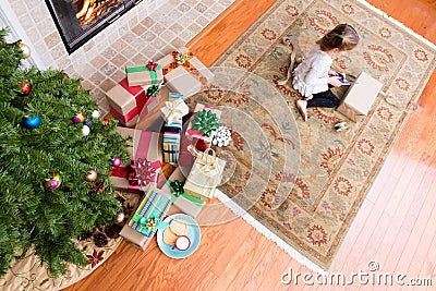 Little girl wrapping Xmas gifts in her living room Stock Photo