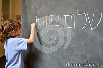 Little girl writes Hello First Grade greetings in Hebrew Stock Photo