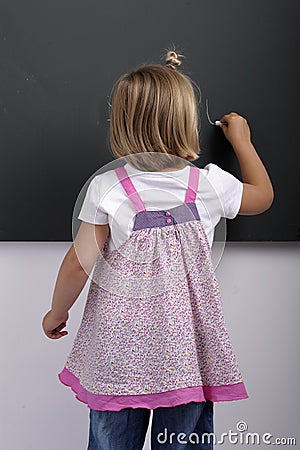 Little girl writing on a cvhalkboard Stock Photo