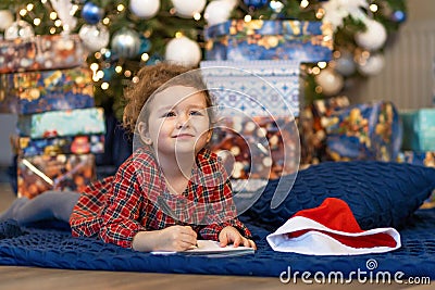 Little girl writing letter to santa. happy kid making a wish, gift, present on new year eve. child dreaming under the christmas Stock Photo