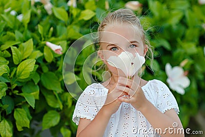 Little girl 5 years blonde smelling a flower in the summer Stock Photo