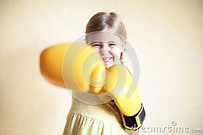 Little girl with yellow boxing gloves over yellow wall background Stock Photo