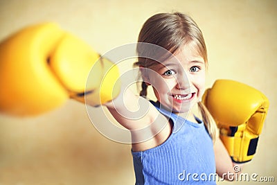 Little girl with yellow boxing gloves over yellow wall background. Girl power concept. Funny little kid portrait. Stock Photo