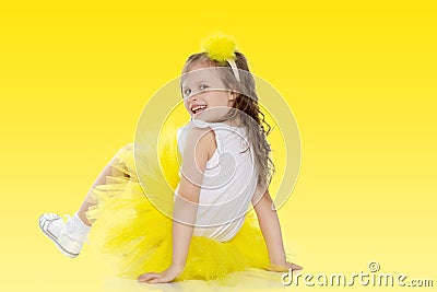 Little girl in a yellow skirt sits on the floor. Stock Photo