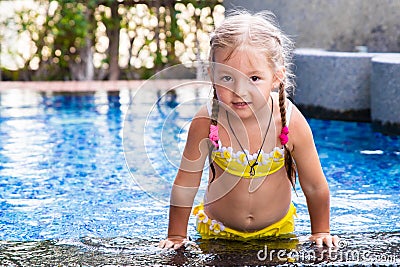 Little girl in a yellow swimsuit in a blue pool like a mermaid. kids concept, kids fashion. Stock Photo