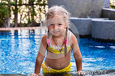 Little girl in a yellow swimsuit in a blue pool like a mermaid. kids concept, kids fashion. Stock Photo