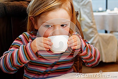 A little girl drinking from a teacup Stock Photo