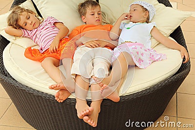 Little girls and boy lying on big circle armchair Stock Photo