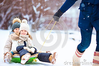 Little girls enjoying sledding. Father sledding his little adorable daughters. Family vacation on Christmas eve outdoors Stock Photo