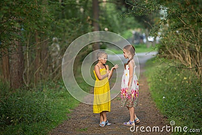 Little girls excitedly talking standing in the green alley. Stock Photo