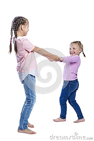 Little girls hold hands and run happily. Children with pigtails in pink sweaters and jeans. Energy and activity in children`s Stock Photo