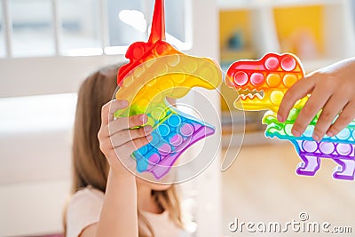 Little girls,kids,sisters play with colorful pop it children room,bedroom.Funny trendy silicone antistress colorful sensory push Stock Photo