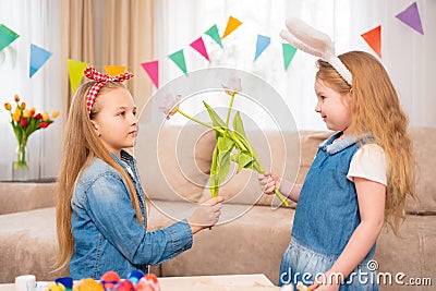 little girls with a red headband and rabbit ears hold pink tulip flower in hands Stock Photo