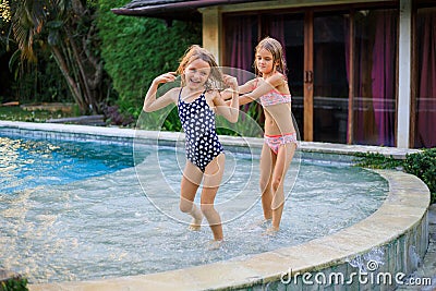 Little girls running in the swimming pool. Sisters playing together. Summer concept. Family activities. Happy childhood. Vacation Stock Photo
