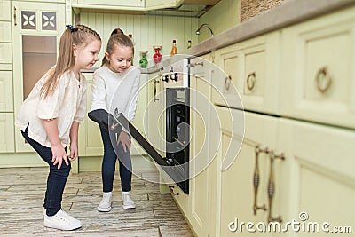 Little girls sisters looks at a tasty cookies in the oven Stock Photo