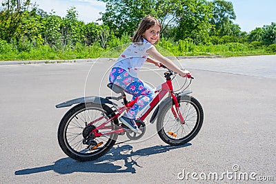 A little happy girl learns to ride a bike in the park Stock Photo