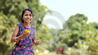 Little happy girl playing with fresh Orange. blurred green background, copy space Selective focus Stock Photo