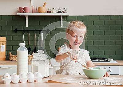 Little happy girl prepares dough in the kitchen. Child pastry chef in the kitchen Stock Photo