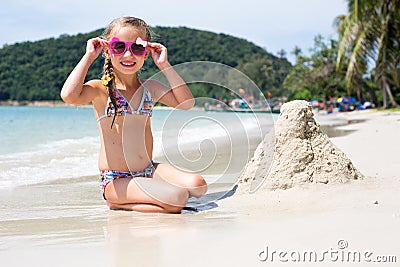 Little happy girl in sunglasses and a swimsuit in the sea. Concept of relaxation and vacation.Girl playing sand on the seashore Stock Photo