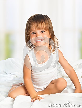 Little happy smiling cheerful girl in a bed Stock Photo