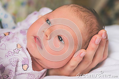 The little head of a newborn baby carefully lies in the palm of mom Stock Photo