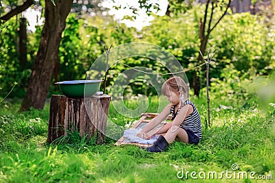 Little helper girl washes clothes using the washboard outdoors Stock Photo