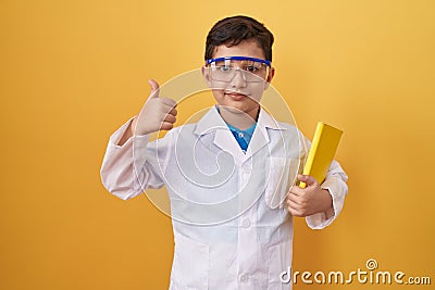 Little hispanic boy wearing scientist glasses smiling happy and positive, thumb up doing excellent and approval sign Stock Photo