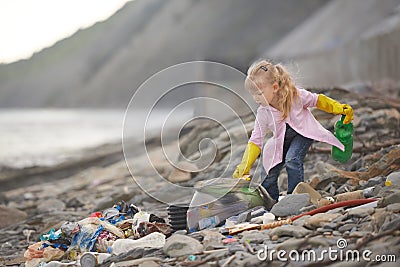 Little janitor picking up garbage at the beach Stock Photo