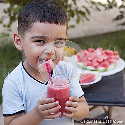 Little kid boy drinks juice from watermelon in summer. Stock Photo