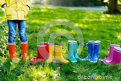 Little kid, boy or girl in jeans and yellow jacket in colorful rain boots. Stock Photo