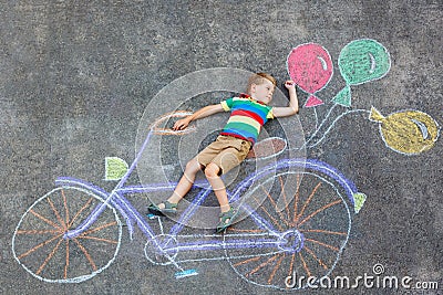 Little kid boy having fun with bicycle chalks picture on ground Stock Photo