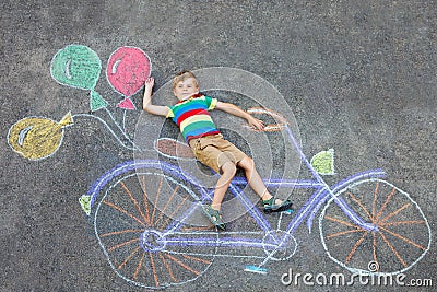 Little kid boy having fun with bicycle chalks picture on ground Stock Photo