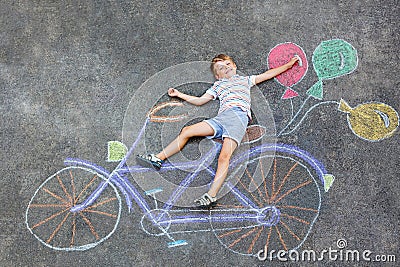 Little kid boy having fun with bicycle chalks picture on ground Stock Photo
