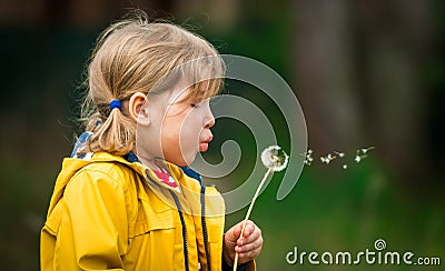 Little kid girl blowing on dandelion. Future generation. Windmills. Renewable energies and sustainable resources - wind Stock Photo