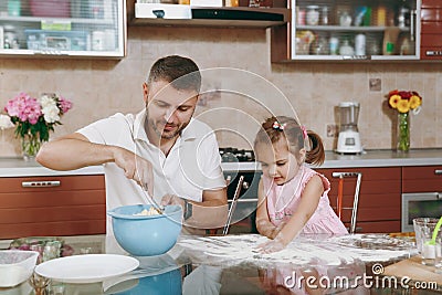 Little kid girl help man to cook Christmas ginger cookies and sprinkling flour in kitchen. Happy family dad, child Stock Photo