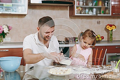 Little kid girl help man to cook lazy dumplings sprinkling flour at table. Happy family dad, child daughter cooking food Stock Photo