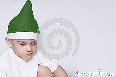 A little kid making a funny annoyed face. Annoyed Christmas Boy in Santa Hat. A really serious and handsome kid Stock Photo