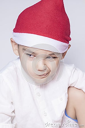 A little kid making a funny annoyed face. Annoyed Christmas Boy in Santa Hat. A really serious and handsome kid Stock Photo
