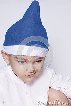 A little kid making a funny annoyed face. Annoyed Christmas Boy in Santa Hat. A really serious and handsome kid Stock Photo