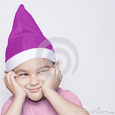 A little kid making funny annoyed face. Annoyed Christmas Boy in Santa Hat Stock Photo