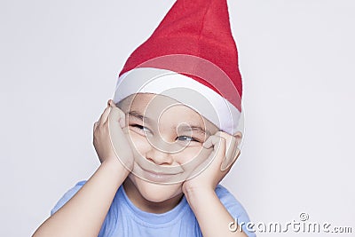 A little kid making funny annoyed face. Annoyed Christmas Boy in Santa Hat Stock Photo