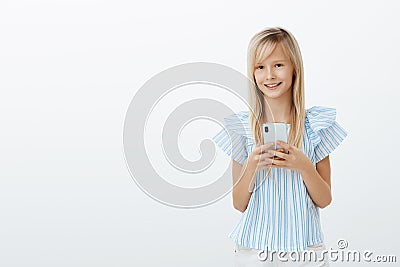 Little kid stole dads cellphone to play games. Portrait of charming happy young girl with blond hair, holding smartphone Stock Photo