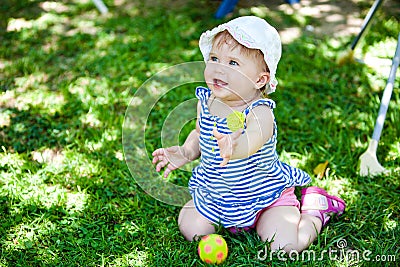 A little kid in the striped shirt is sitting on the grass Stock Photo