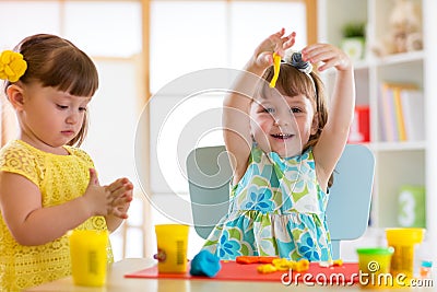 Little kids having fun together with colorful modeling clay at daycare. Creative kids molding at home. Children girls Stock Photo