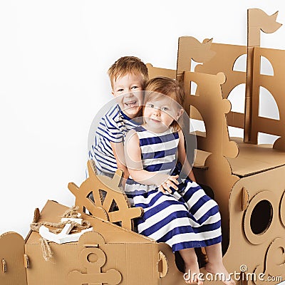 Little kids playing with cardboard ship on white background. Hap Stock Photo