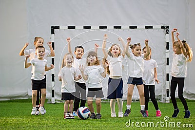 Little kids playing football indoors. Children football team. Hands up and jumping Stock Photo